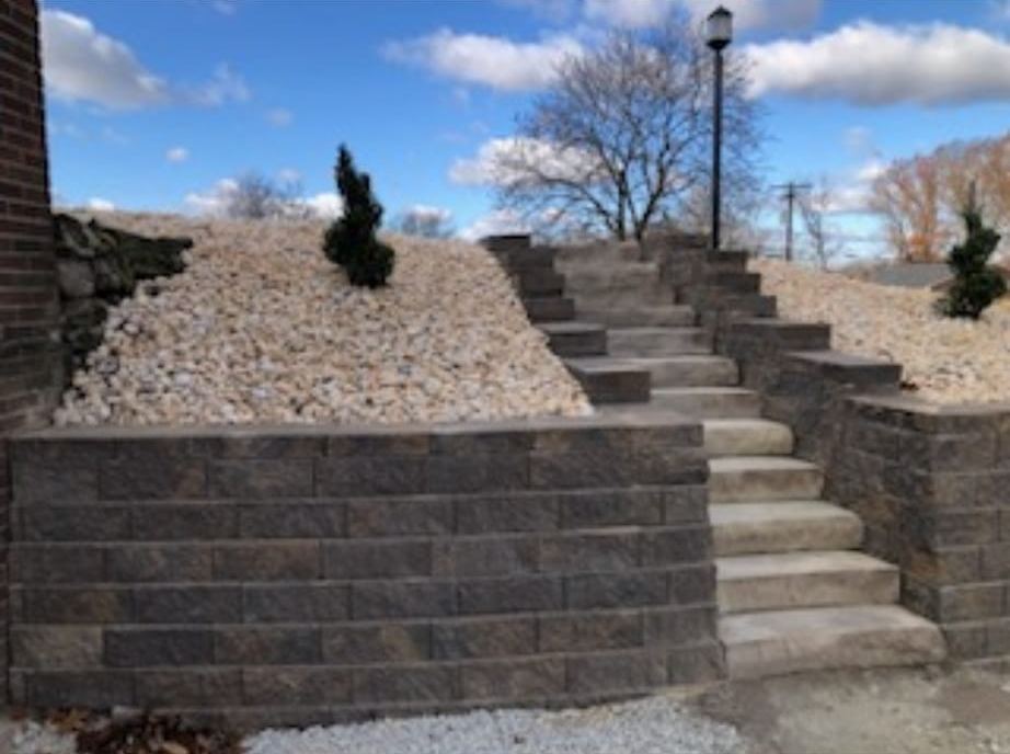 Block retaining wall with built-in stone steps and gravel slope